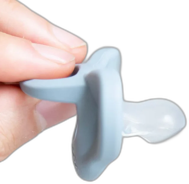 A hand holding the patented Minbie orthodontic pacifier