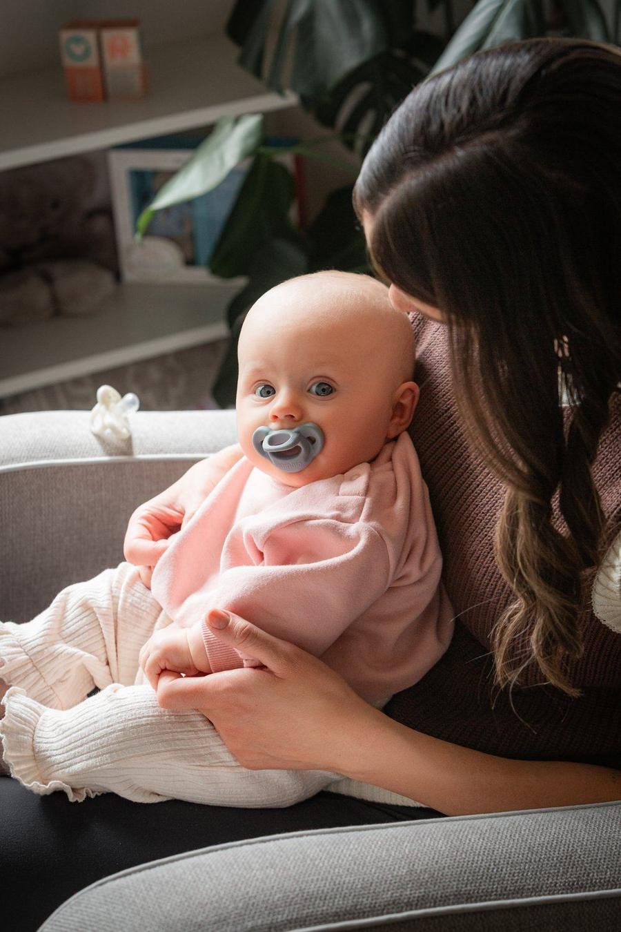 A parent soothing a baby with a Minbie pacifier