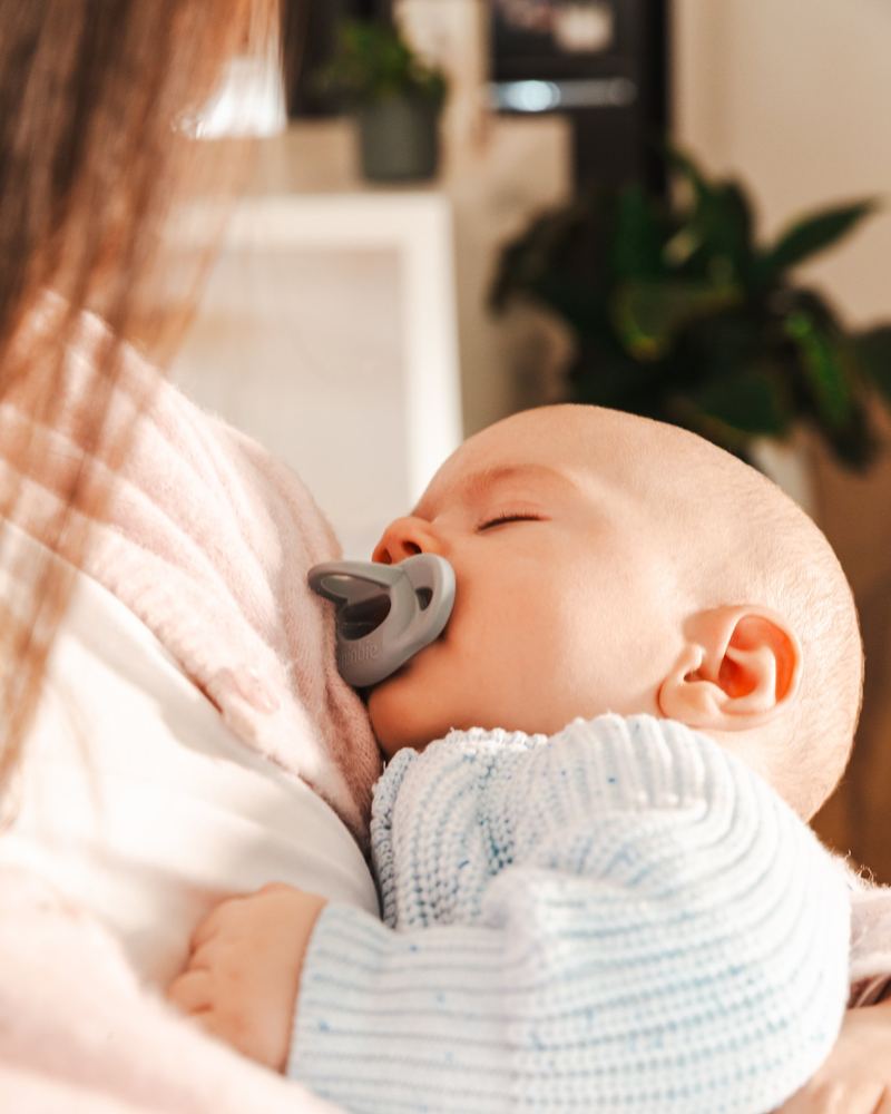 A sleeping baby with a Grey Minbie pacifier