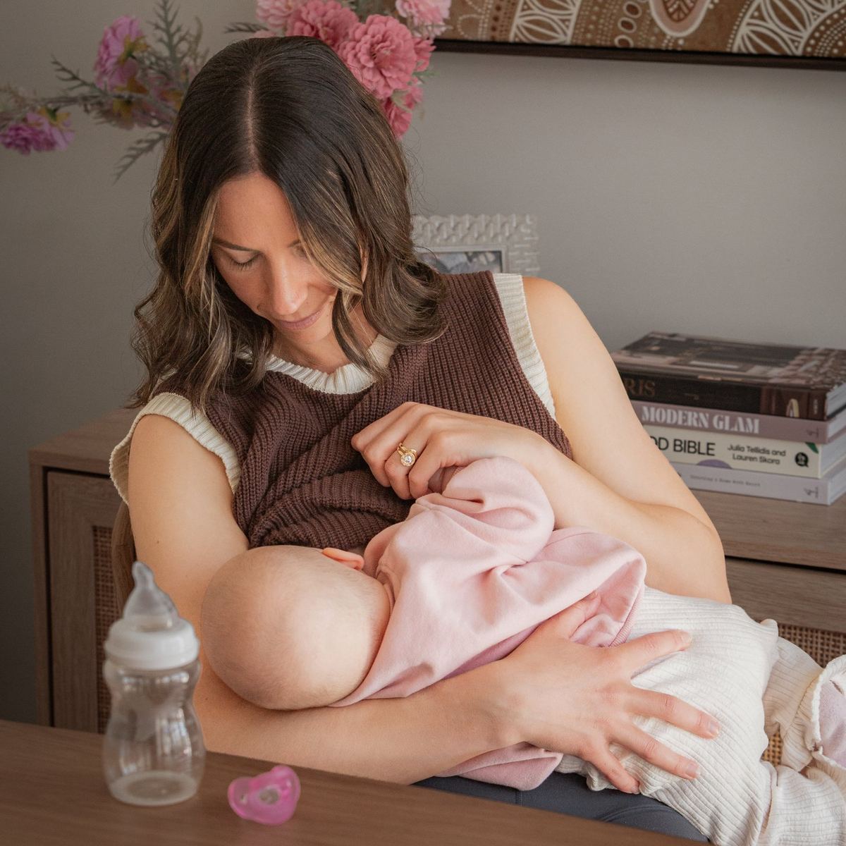A mom breastfeeding her baby with a Minbie bottle nearby