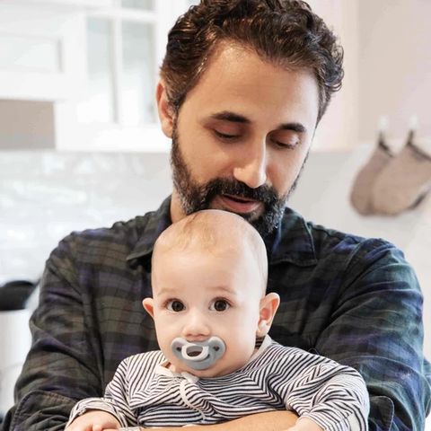 Dr Omar Breik holding his baby, who has a Minbie pacifier